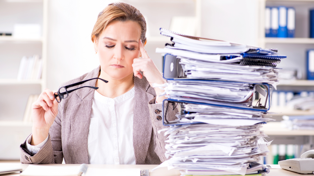Stacks of paperwork and a stressed professional